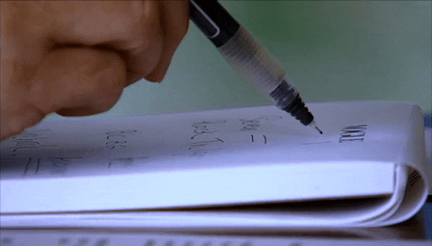 Uma pessoa escrevendo num bloco de papel com uma caneta