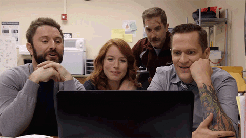 Imagem animada em que uma mulher, em frente ao computador, e três homens ao seu redor, que comentam algo com ar de satisfação.